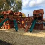Wooden playground with slides and sand area on a sunny day